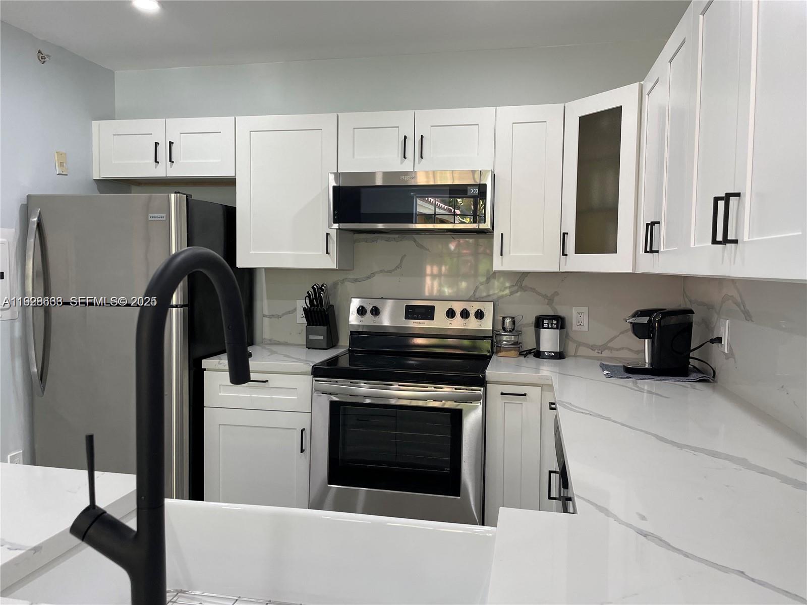 2031 Renaissance Boulevard, Unit 101 Miramar, FL 33025 - Photo 2 of 23 a kitchen with stainless steel appliances granite countertop a stove and a refrigerator