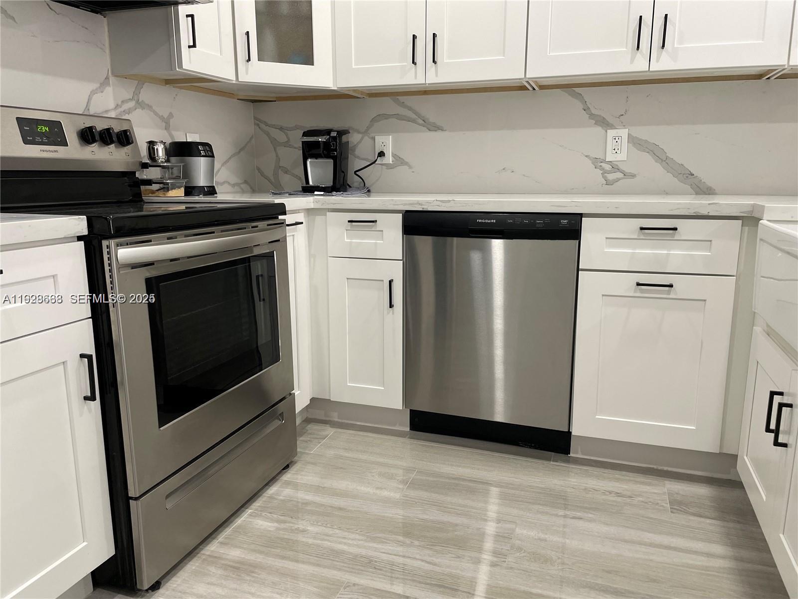 2031 Renaissance Boulevard, Unit 101 Miramar, FL 33025 - Photo 4 of 23 a kitchen with stainless steel appliances granite countertop a stove a sink and white cabinets