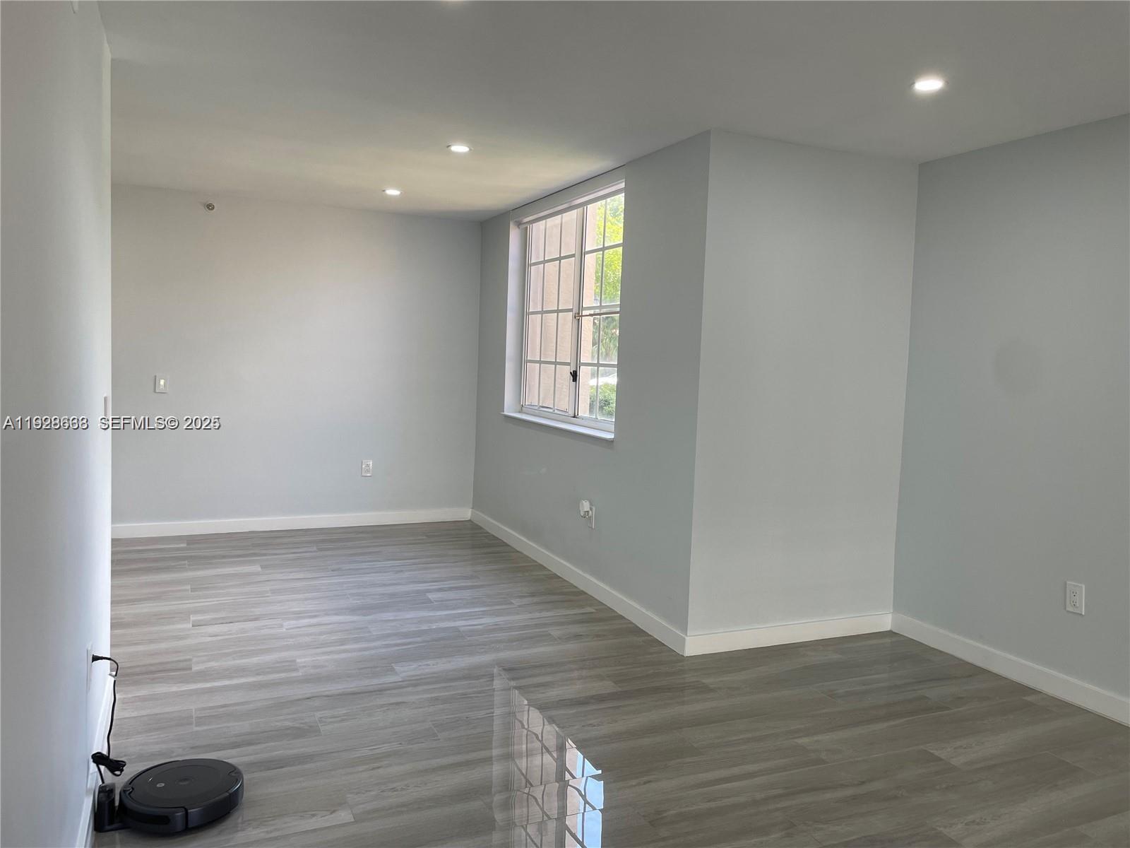 2031 Renaissance Boulevard, Unit 101 Miramar, FL 33025 - Photo 9 of 23 a view of an empty room with wooden floor and a window