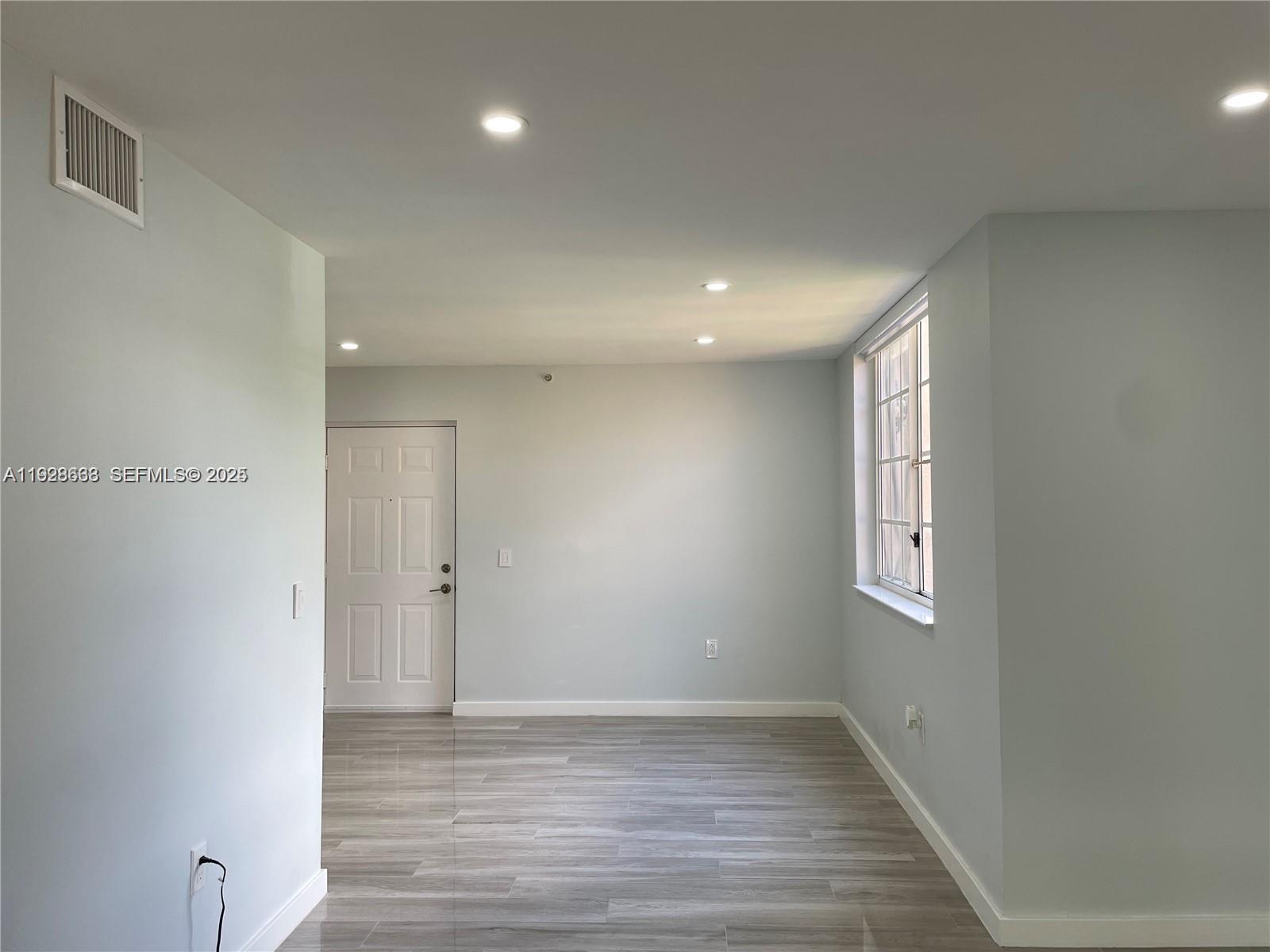 2031 Renaissance Boulevard, Unit 101 Miramar, FL 33025 - Photo 10 of 23 a view of an empty room with wooden floor and a window