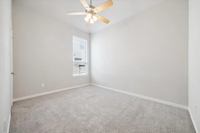 an empty room with a chandelier fan and windows