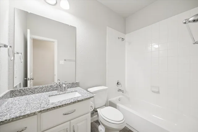 a bathroom with a granite countertop sink a toilet and shower