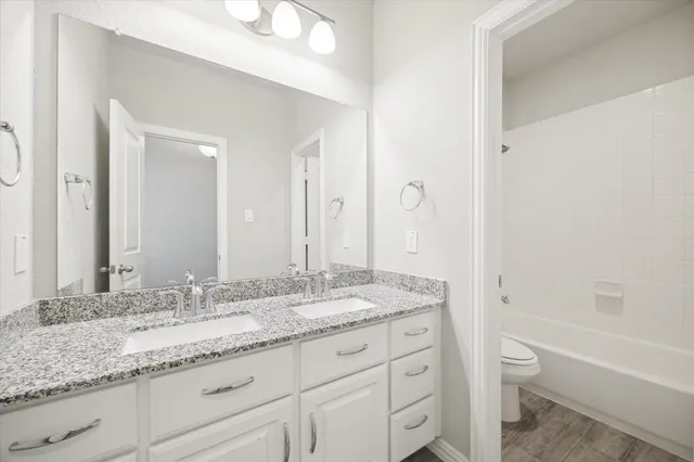 a bathroom with a granite countertop sink a toilet and bathtub