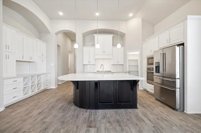a kitchen with stainless steel appliances a kitchen island wooden floors and white cabinets