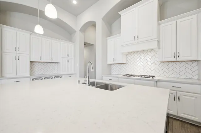 a kitchen with granite countertop a sink a stove a refrigerator and white cabinets