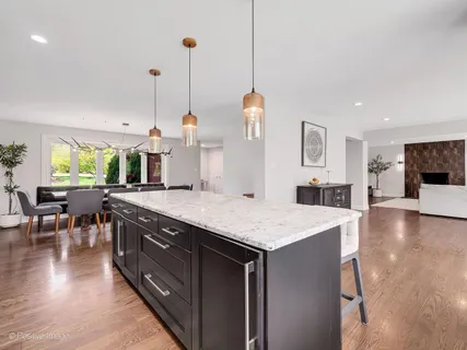 a kitchen with stainless steel appliances granite countertop wooden cabinets a stove top oven a dining table and chairs with wooden floor