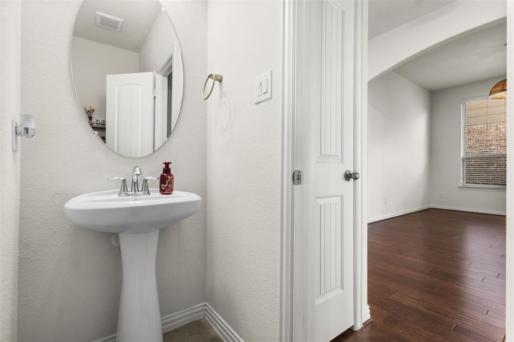 1740 Rio Costilla Road Fort Worth, TX 76131 - Photo 22 of 40 Pedestal sink with chrome faucet, oval wall mirror, and wood-finish flooring