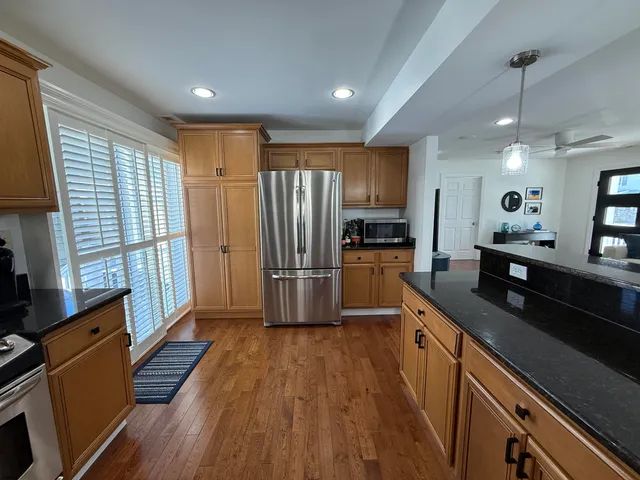 a kitchen with granite countertop a refrigerator a sink and white cabinets