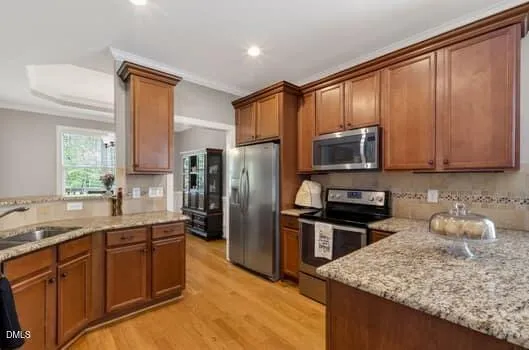 a kitchen with stainless steel appliances kitchen island granite countertop a stove a refrigerator a sink a dining table and chairs with wooden floor