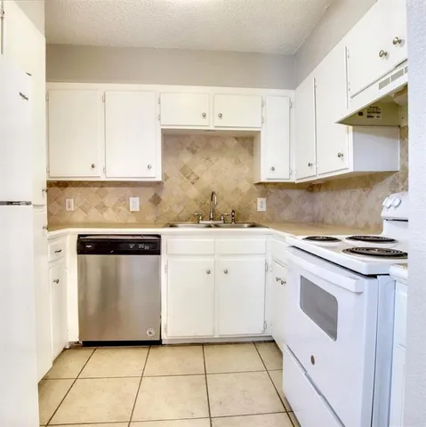 a kitchen with granite countertop white cabinets stainless steel appliances and a sink