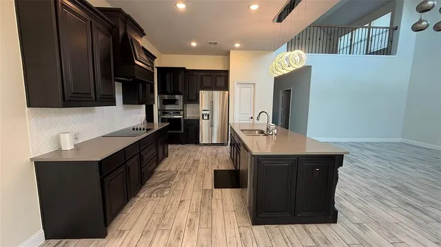 a kitchen with a sink refrigerator and wooden floor