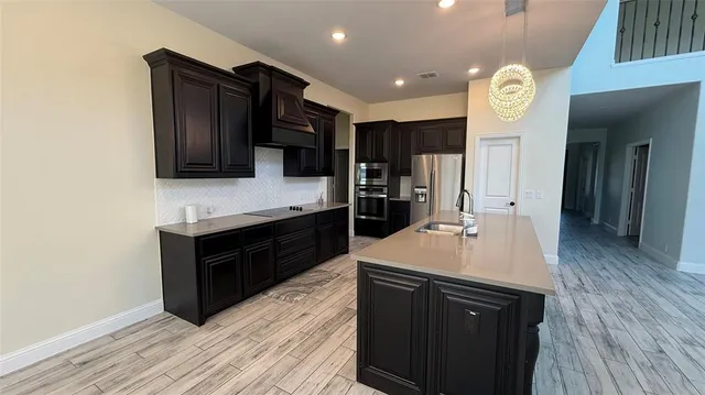 a kitchen with a sink and a stove top oven with wooden floor