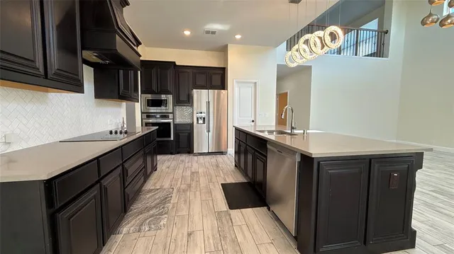 a kitchen with stainless steel appliances a refrigerator a sink and wooden cabinets
