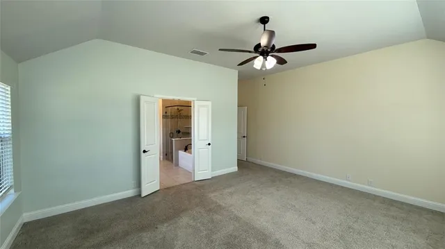 an empty room with a chandelier fan and windows