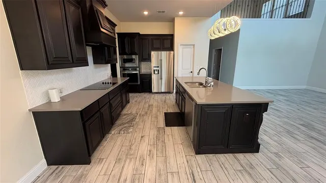 a kitchen with stainless steel appliances granite countertop wooden floors a refrigerator and a stove