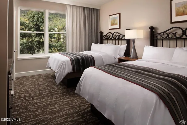 a bedroom with two beds and a large window