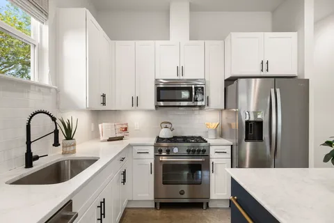 a kitchen with stainless steel appliances a white kitchen island a sink a stove and refrigerator