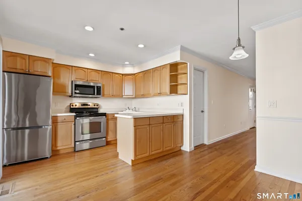 a kitchen with granite countertop stainless steel appliances a refrigerator cabinets and wooden floor