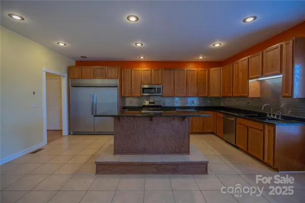 a kitchen with stainless steel appliances granite countertop a stove a sink and a refrigerator