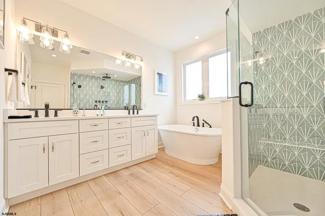 a bathroom with a granite countertop sink vanity mirror bathtub shower and a bathtub