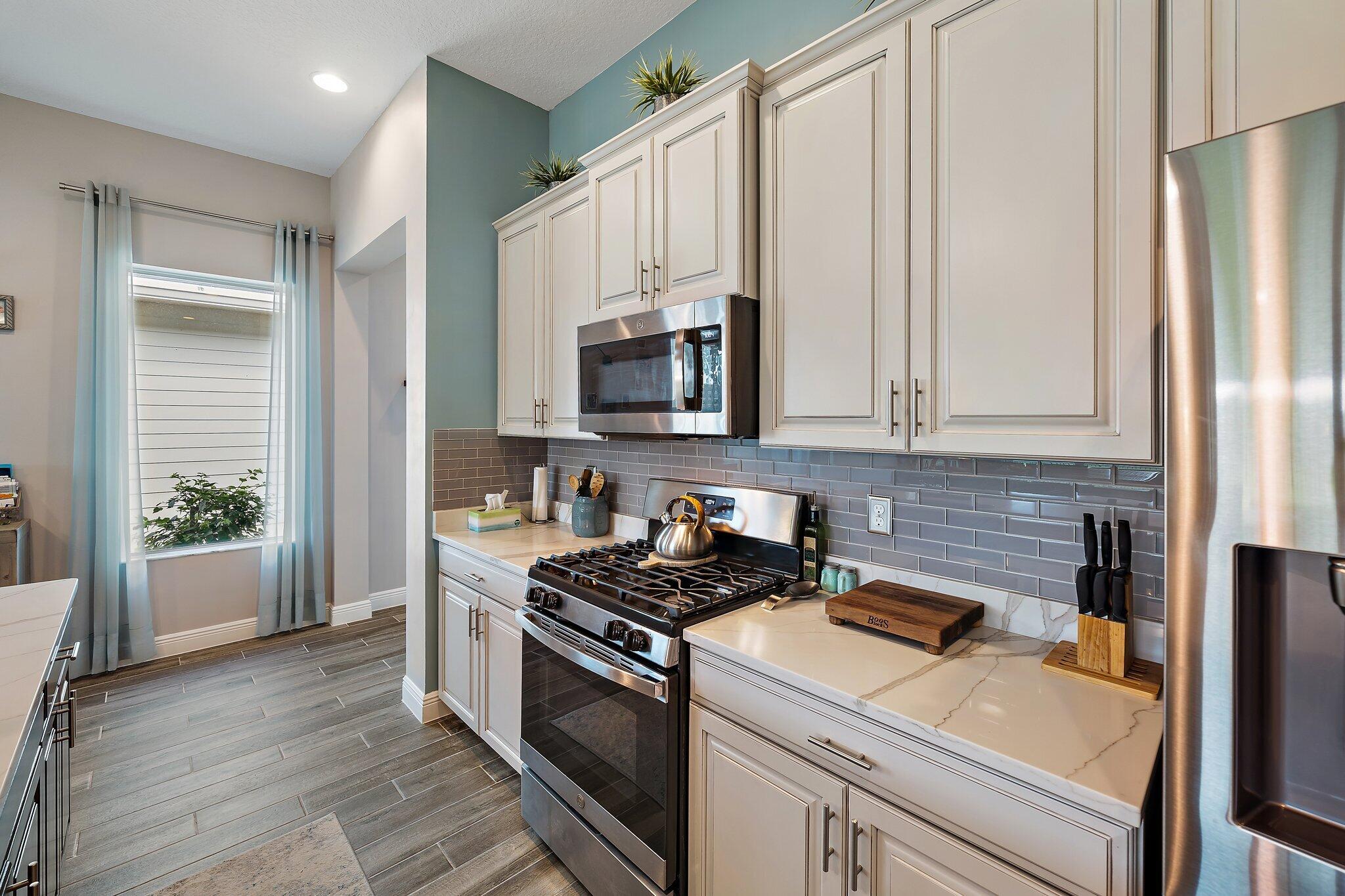 19540 Wheelbarrow Bend Loxahatchee, FL 33470 - Photo 11 of 54 a kitchen with stainless steel appliances a stove a microwave and a refrigerator