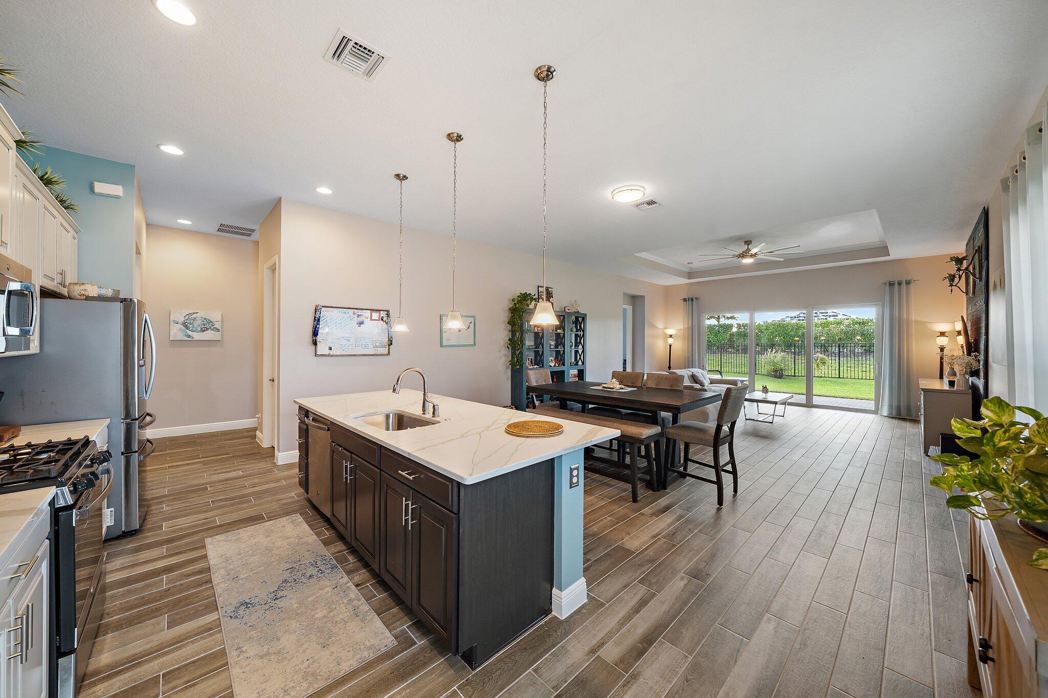 19540 Wheelbarrow Bend Loxahatchee, FL 33470 - Photo 7 of 54 a large kitchen with kitchen island a sink table and chairs