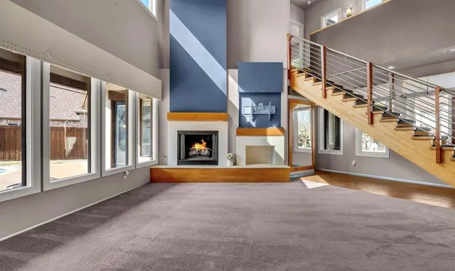 a view of an empty room with fireplace and windows