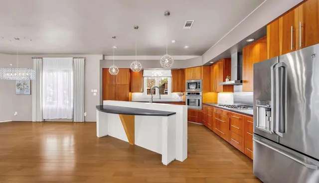 a kitchen with stainless steel appliances a center island wooden floor and a large window