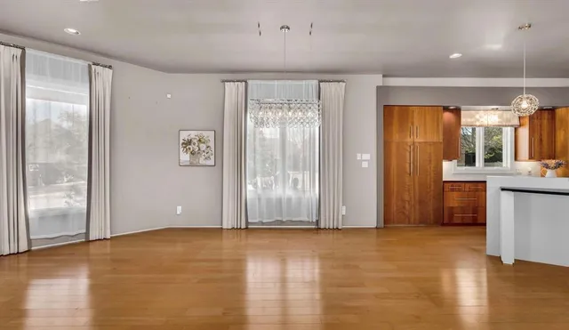 a view of an empty room with window and wooden floor