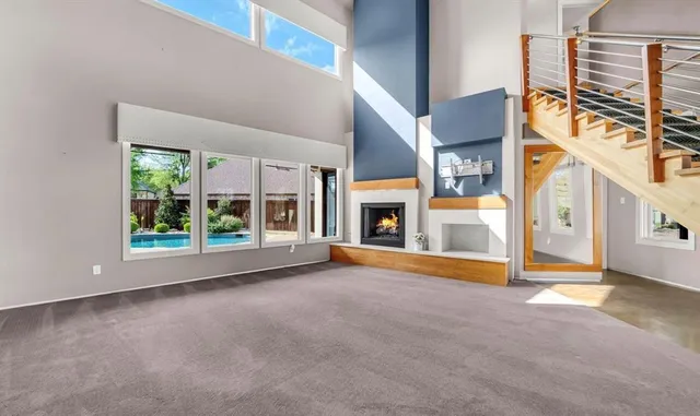 a view of an empty room with fireplace and windows