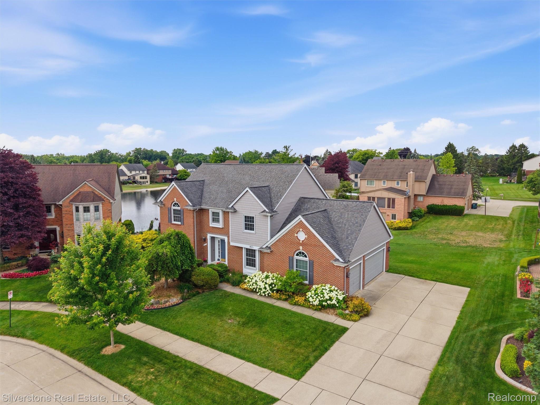 6577 Edith Court Troy, MI 48085 - Photo 6 of 61 Brick and siding exterior with a multi-car driveway, attached garage, and mature landscaping