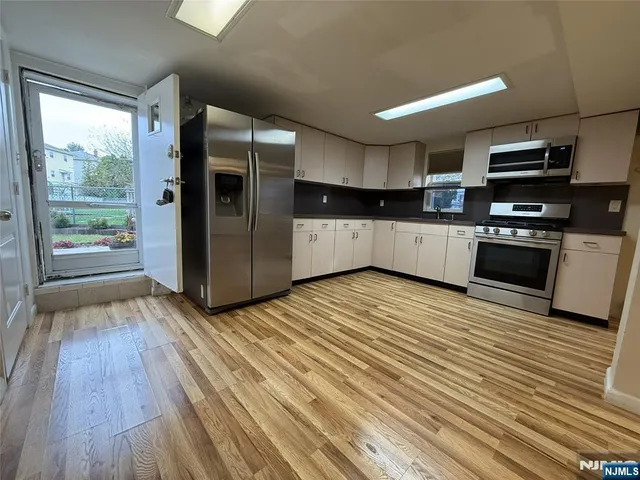 a kitchen with stainless steel appliances a refrigerator and wooden floor