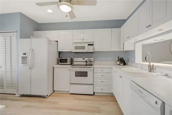 a kitchen with white cabinets and white appliances