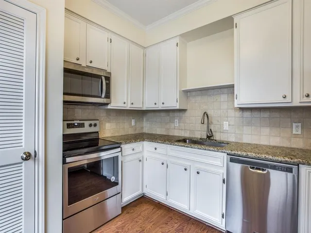 a kitchen with granite countertop white cabinets and stainless steel appliances