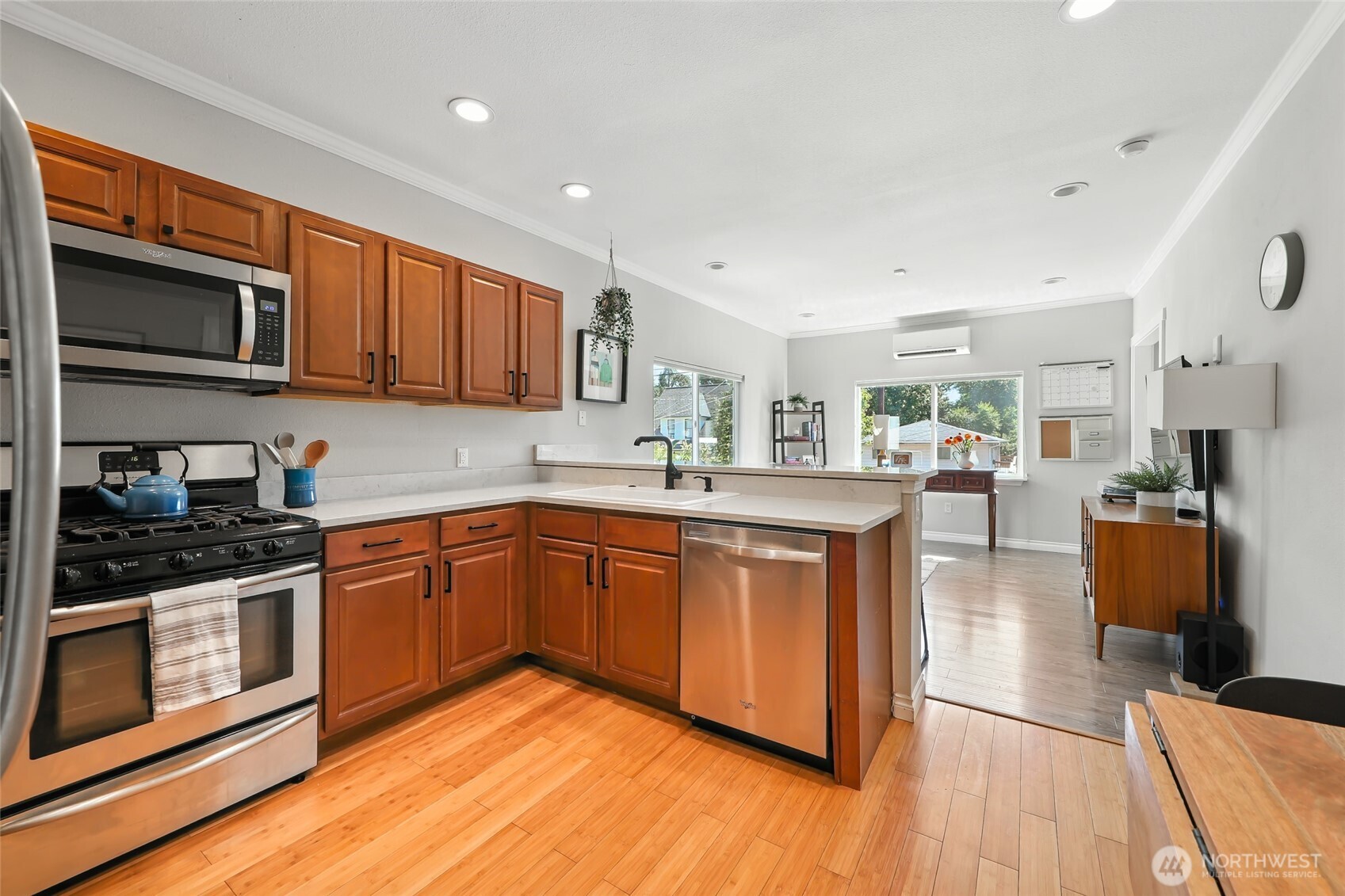 4616 South Orcas Street Seattle, WA 98118 - Photo 10 of 37 a kitchen with stainless steel appliances granite countertop wooden cabinets a sink a stove a microwave and wooden floors
