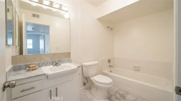 a bathroom with a toilet a sink a mirror and a bathtub