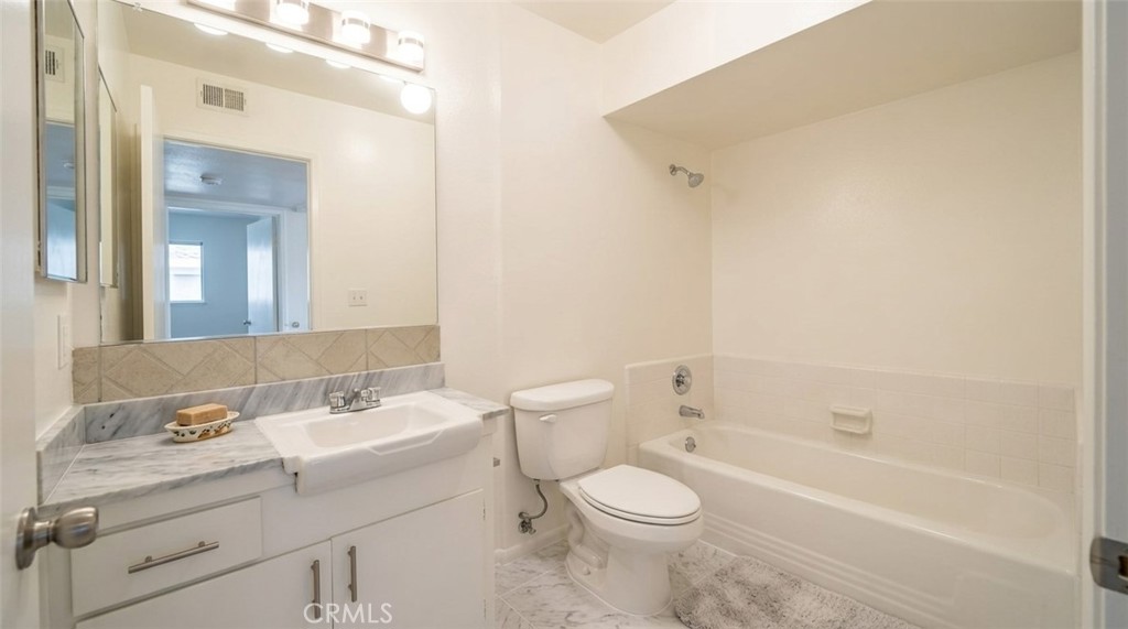 27077 El Rancho Drive Menifee, CA 92586 - Photo 6 of 11 a bathroom with a toilet a sink a mirror and a bathtub