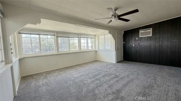 an empty room with chandelier fan and windows