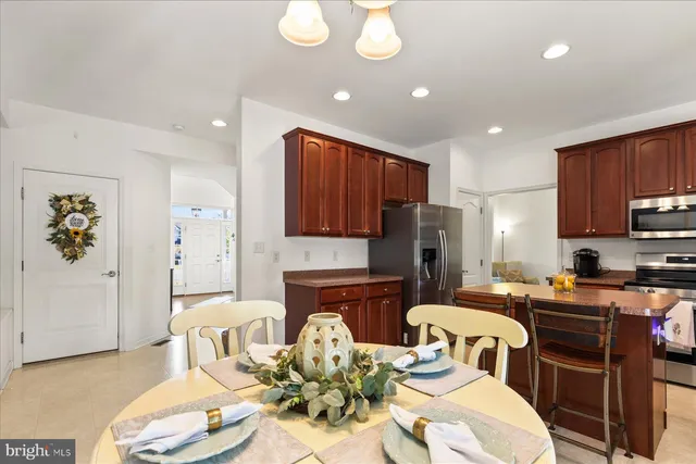 a kitchen with stainless steel appliances granite countertop a refrigerator a stove a sink a dining table and chairs with wooden floor