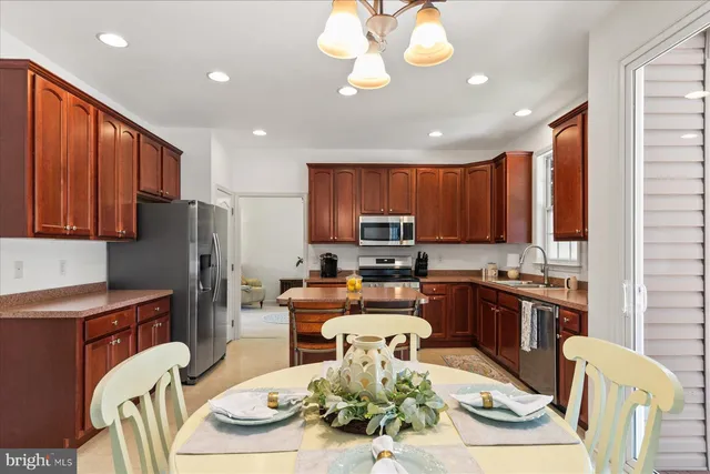a kitchen with stainless steel appliances granite countertop a refrigerator a stove top oven a sink dishwasher a dining table and chairs with wooden floor