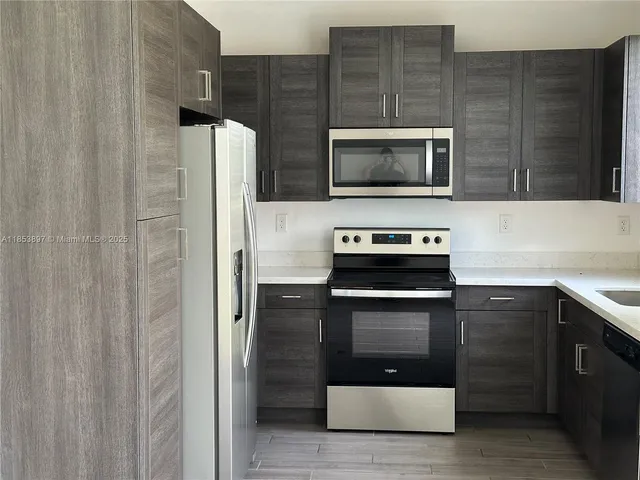 a kitchen with stainless steel appliances a stove a microwave and a sink