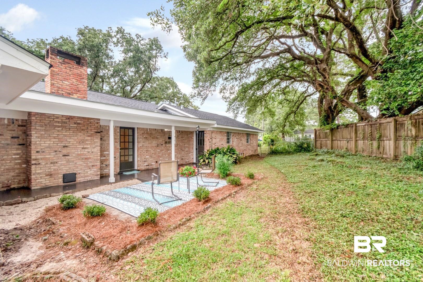5217 Perin Road Mobile, AL 36693 - Photo 35 of 45 Expansive backyard featuring a mature tree, wood privacy fencing, and a brick exterior home with an extended covered patio