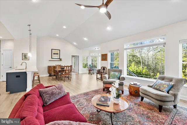 a living room with furniture kitchen view and a large window