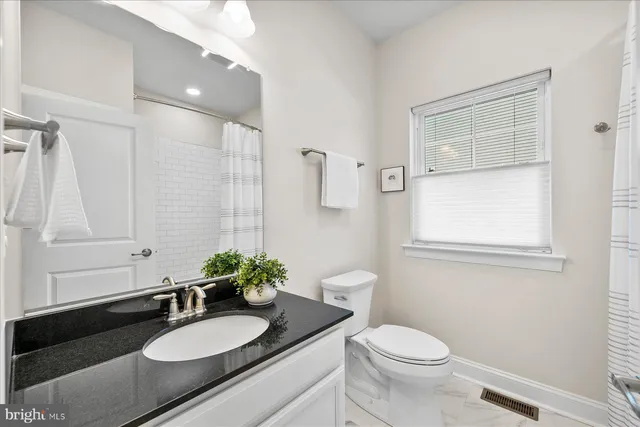 a bathroom with a granite countertop sink toilet a mirror and shower