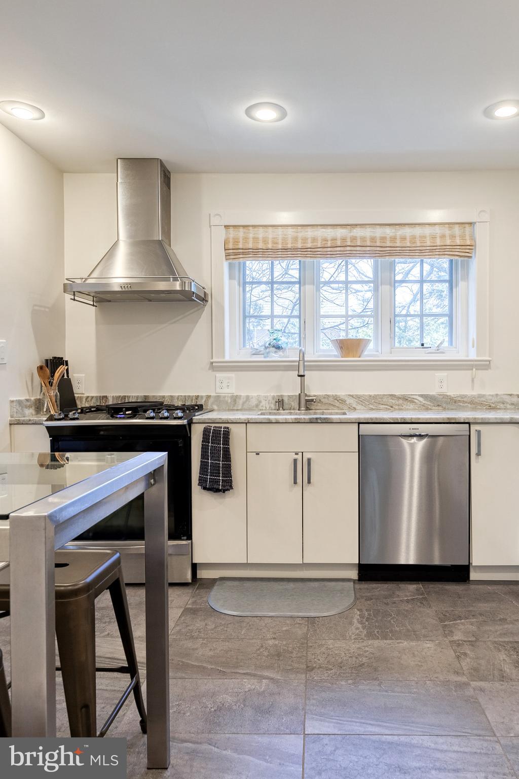 4010 Roundtop Road Baltimore, MD 21218 - Photo 14 of 51 a white kitchen with granite countertop a stove a sink dishwasher and white cabinets with wooden floor
