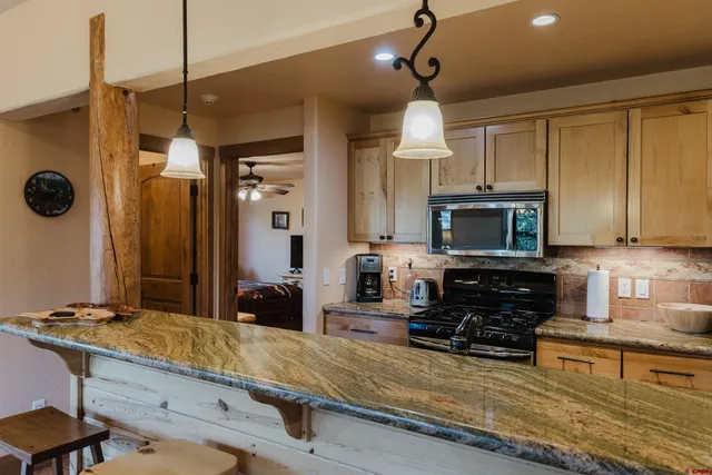 a kitchen with stainless steel appliances granite countertop a sink a stove and a wooden cabinets
