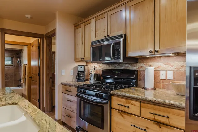 a kitchen with granite countertop wooden cabinets stainless steel appliances and a counter space