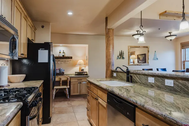 a kitchen with granite countertop stainless steel appliances a sink stove and refrigerator