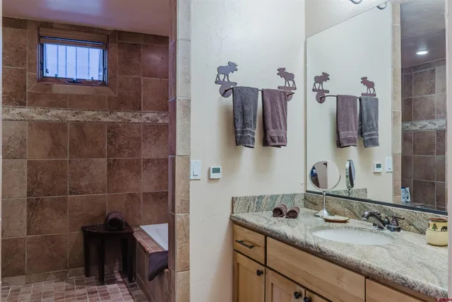 a bathroom with a granite countertop sink a mirror and shower