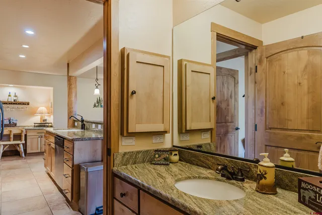 a bathroom with a granite countertop double vanity sink and mirror